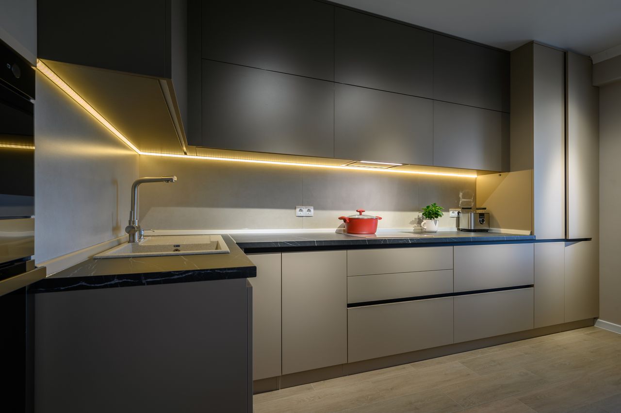 Sleek dark gray kitchen with warm LED undercabinet lighting and marble counters