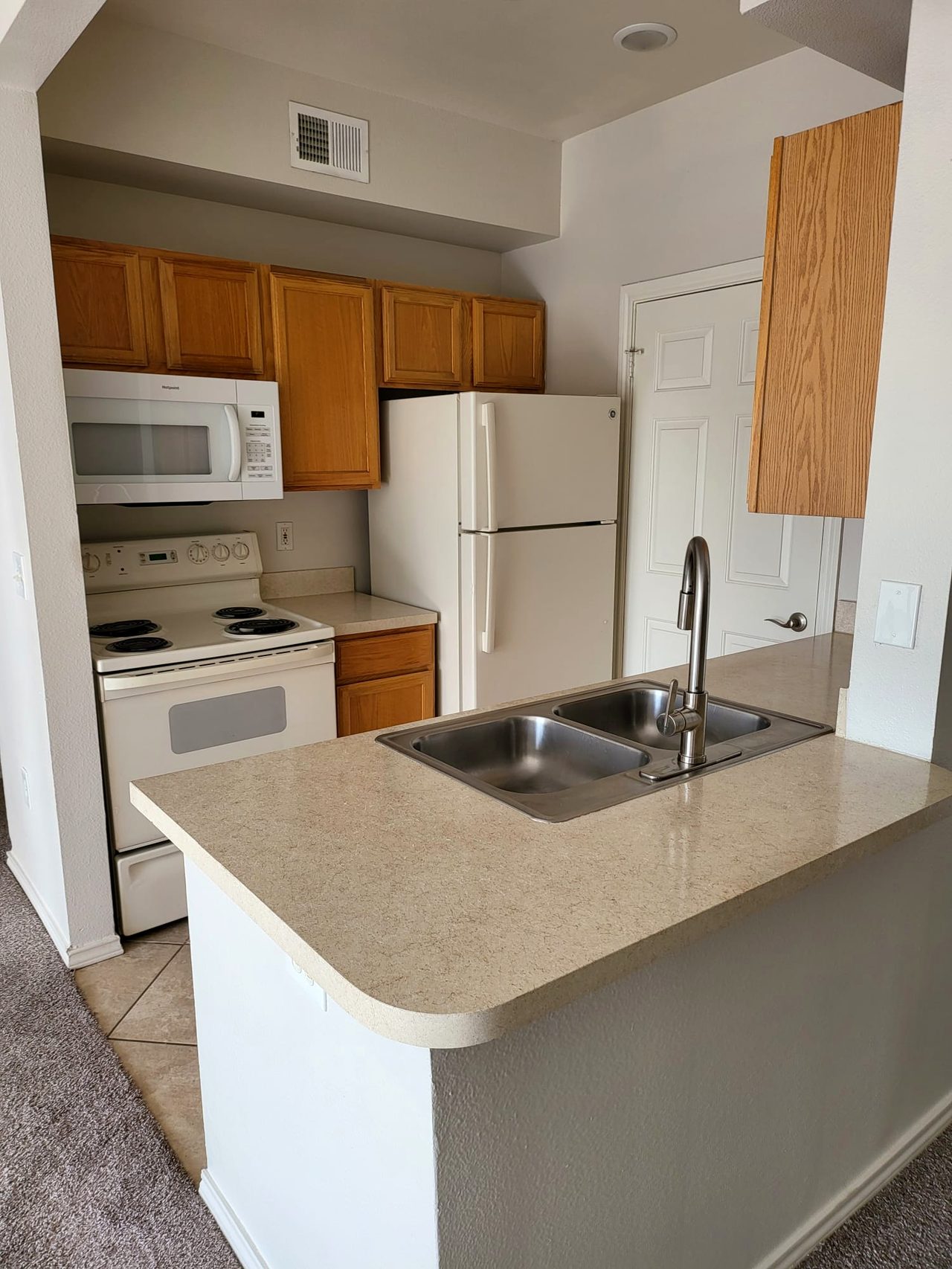 Kitchen before — dated oak cabinets and beige laminate counters
