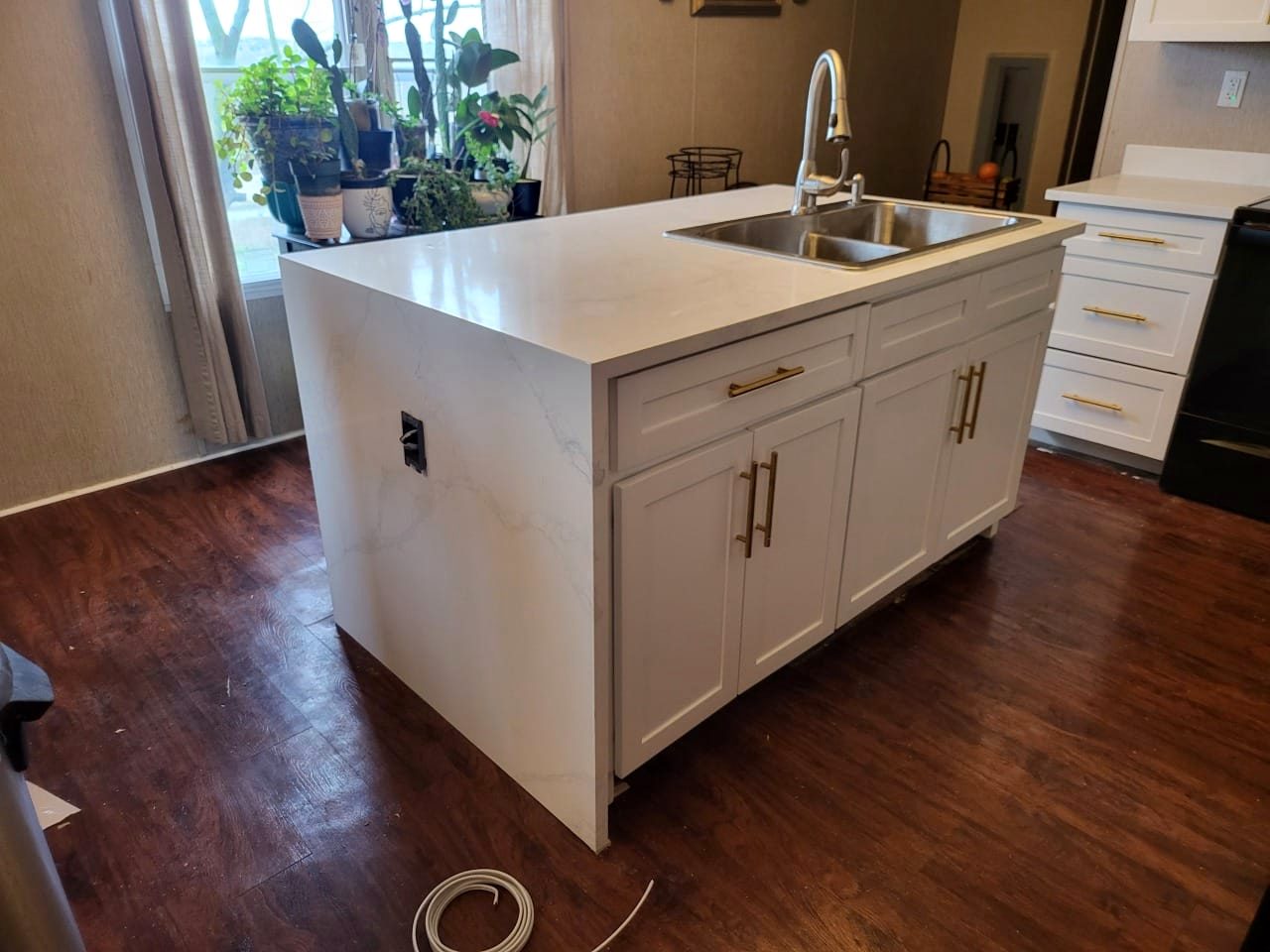 White shaker kitchen with quartz waterfall island and brass hardware by Alex Rodriguez
